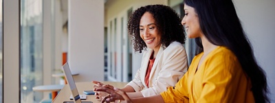 Two women smiling looking at laptop