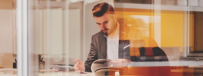 A man in a suit reading through a book of IT certifications