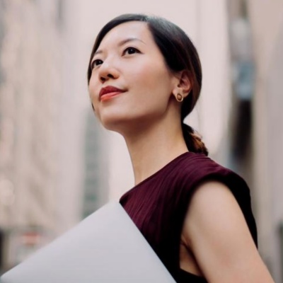 Woman holding laptop looking into the distance.