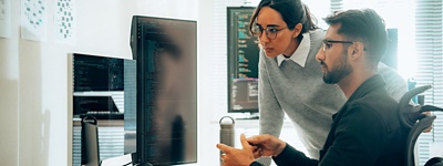 Two employees working at a computer in an office setting