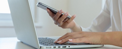 Person holding a phone while working on a laptop