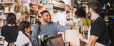 People in a grocery store checkout line talking to the clerk.