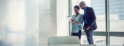Due colleghi che lavorano insieme su un tablet in una sala conferenze dell'ufficio