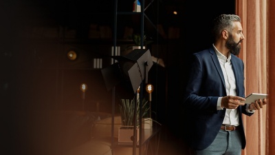 Businessperson holding a tablet looks out a window