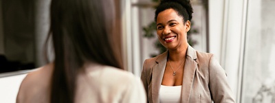 Woman in blazer smiling at person facing her