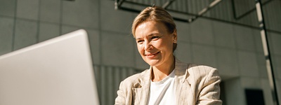 Woman in blazer smiling looking at computer