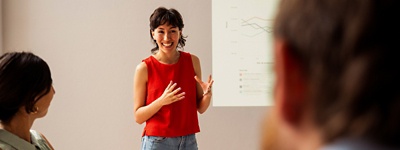 Woman in front of room presenting to colleagues
