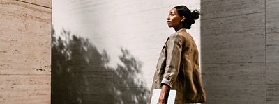 Woman in blazer looking up to the side holding laptop