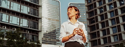 Woman on smartphone in front of buildings