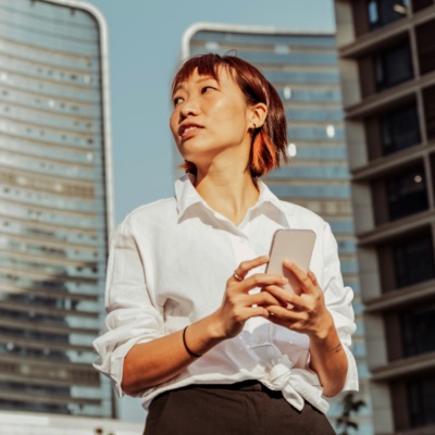 Woman on smartphone in front of buildings