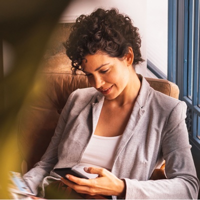 A woman sat in an office looking at her phone