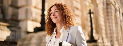 Una donna con i capelli ricci che sorride tenendo in mano dei documenti finanziari