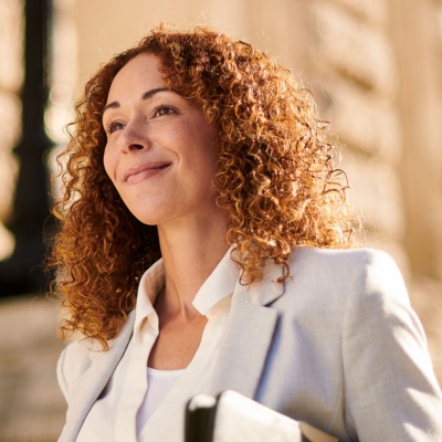 A woman with curly hair smiling while holding a document of financial files