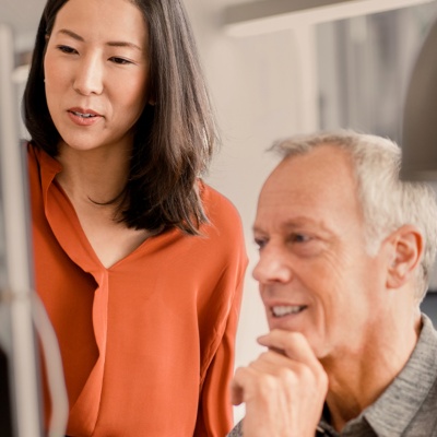 Woman standing man sitting looking at laptop
