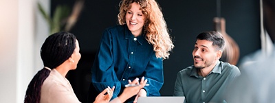 Woman standing up talking to colleagues smiling