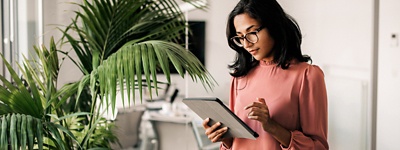 Woman with glasses looking at tablet in office