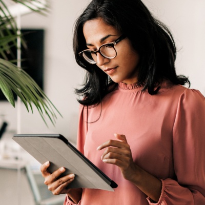 Woman with glasses looking at tablet in office