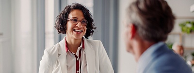 Woman with glasses smiling in conversation with coworker