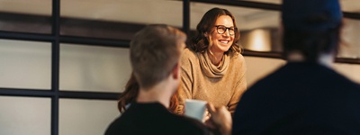 Woman with glasses speaking to two coworkers