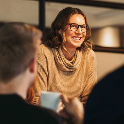 Woman with glasses speaking to two coworkers