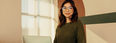 Woman with glasses standing with computer