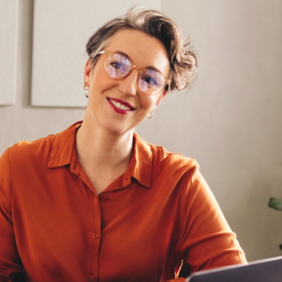 Woman with short hair and glasses looking at person smiling