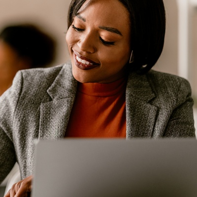 woman writing sitting at desk with laptop