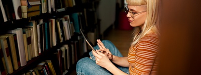 Woman in a library next to bookshelves