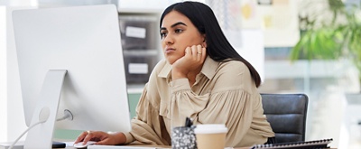 Empleada insatisfecha sentada en un escritorio mirando un ordenador