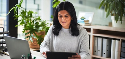 Employee working on a tablet and laptop at a desk