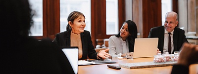 Professionally dressed women and men sitting at table in a meeting room having a conversation